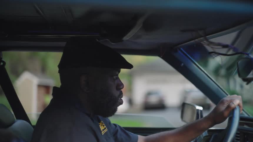 A man wearing a beret driving a car