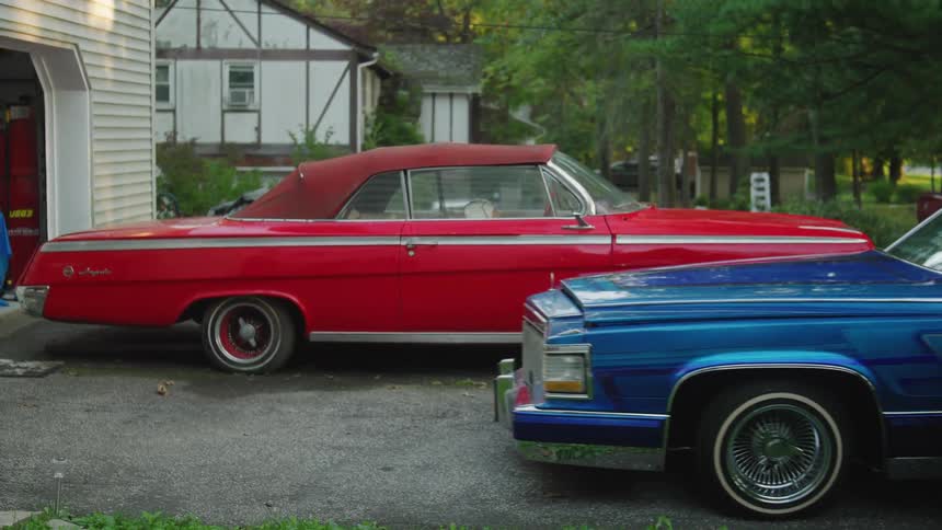 Man backs his artistically painted vintage car in the driveway on a summer day