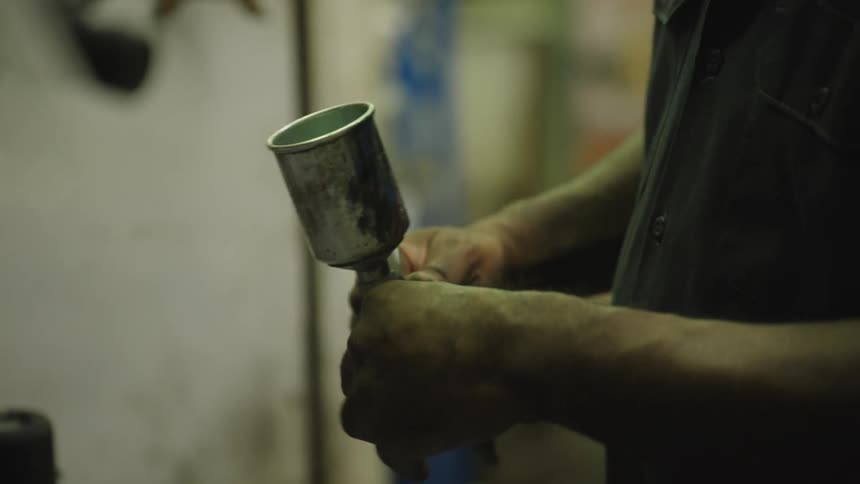 The painter adjusts the knob on his spray gun