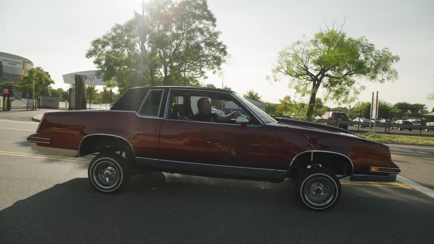Man operates a vehicle with a suspension that can be manipulated while in a parking lot