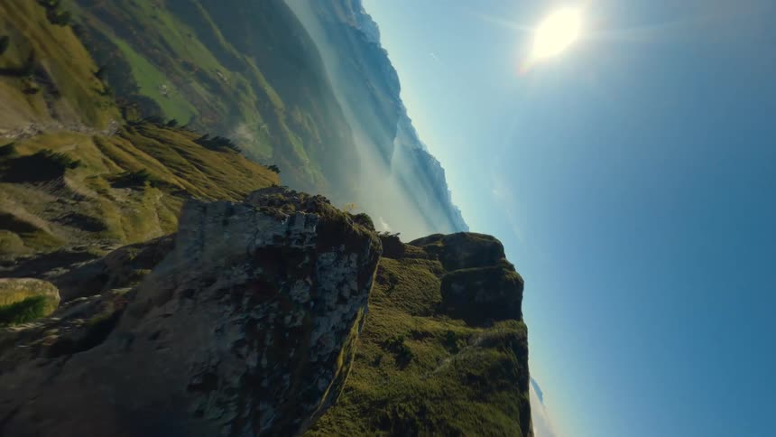 Aerial view of a mountain ridge above a misty valley under a clear sky in Switzerland