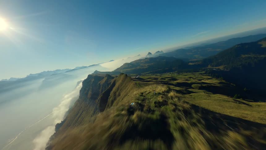 Mountain ridge rises from a foggy valley under the bright sun