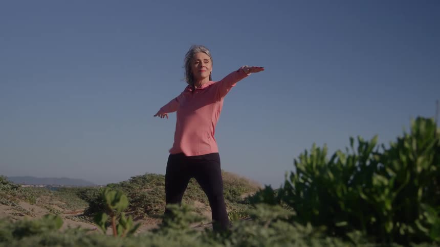 A woman is doing a yoga stretch on a mountaintop