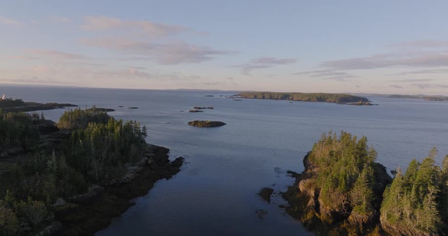Aerial view of forested islands scattered across the ocean under a pastel sky