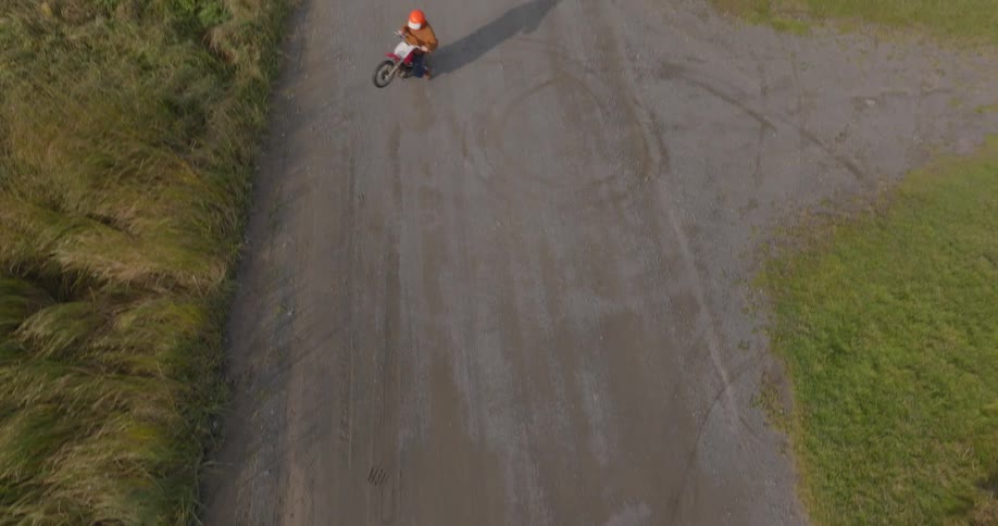 Two people ride around the road with their dirt bikes