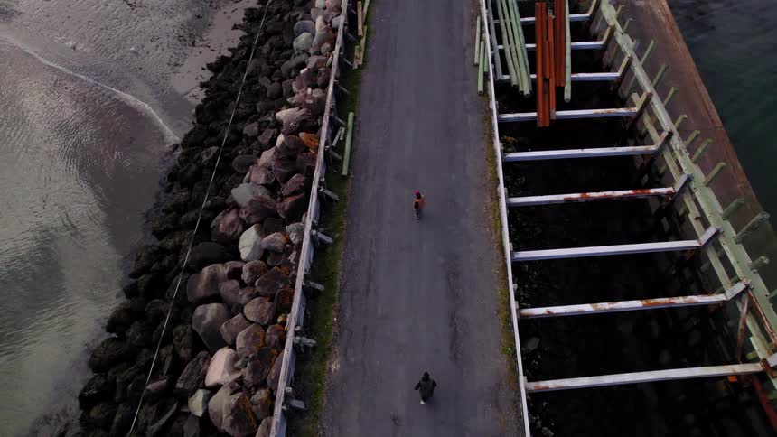 Two men are skateboarding on the shore trail