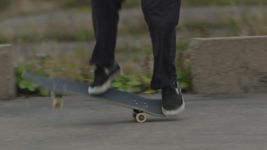 Person wearing black pants and dark sneakers missing a skateboard trick in an urban area