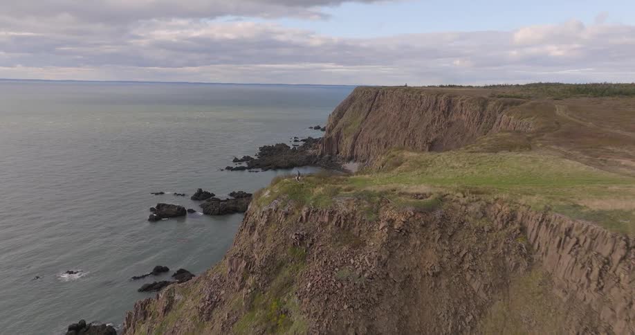 Aerial view of rocky cliffs and beach by the sea under a overcast sky