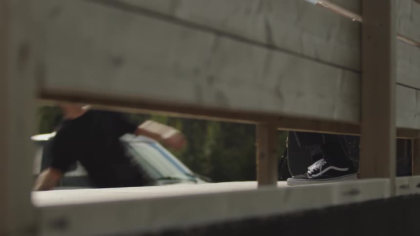 A person rides a skateboard on a ramp in a skate park at midday