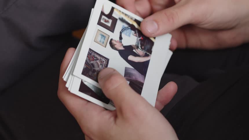 Close up of a person shifting through a stack of old polaroid photos