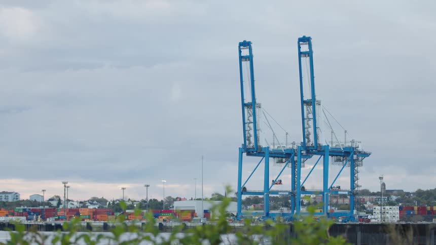 Industrial port with cranes and numerous containers in the harbor at sunset