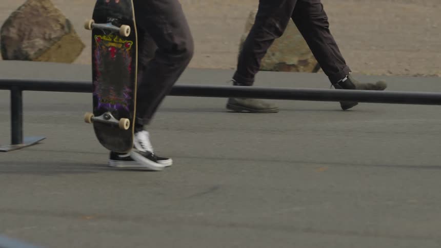 Two men walking on a road outdoors while holding their skateboards