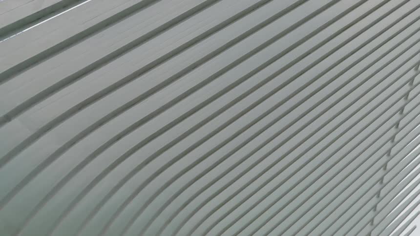 Architectural structure composed of curved vertical white beams forming a symmetrical pattern