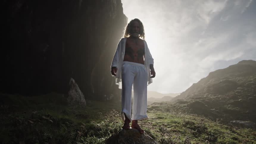 The man is wearing all white on the rocks