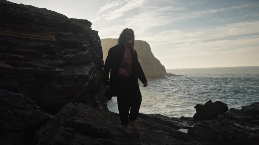 The man walks barefoot on the rocks of the shore