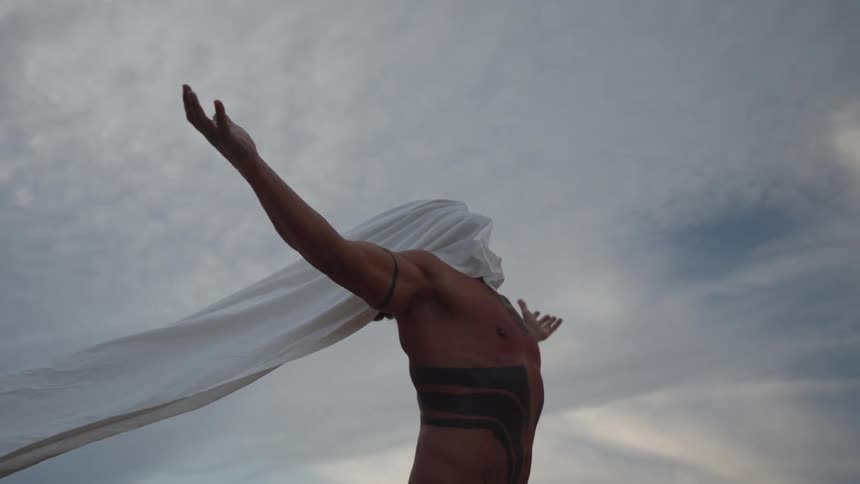 The man is standing with a shirt over his head and arms out