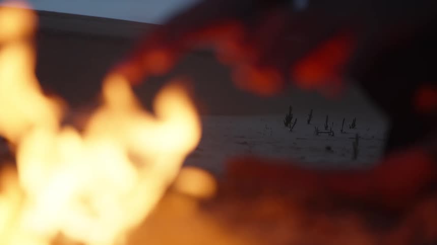 An open wood fire creates warm blurs of orange flame in the foreground and background at night