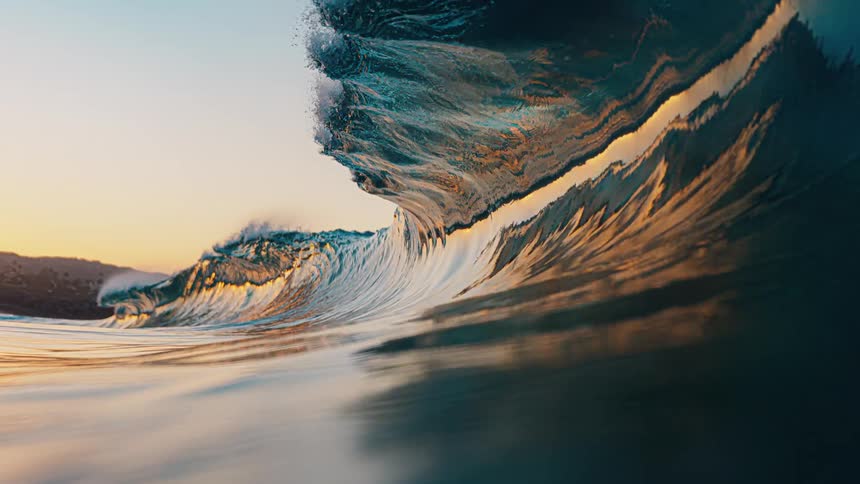Large wave breaks near the coast under a red tinted sky