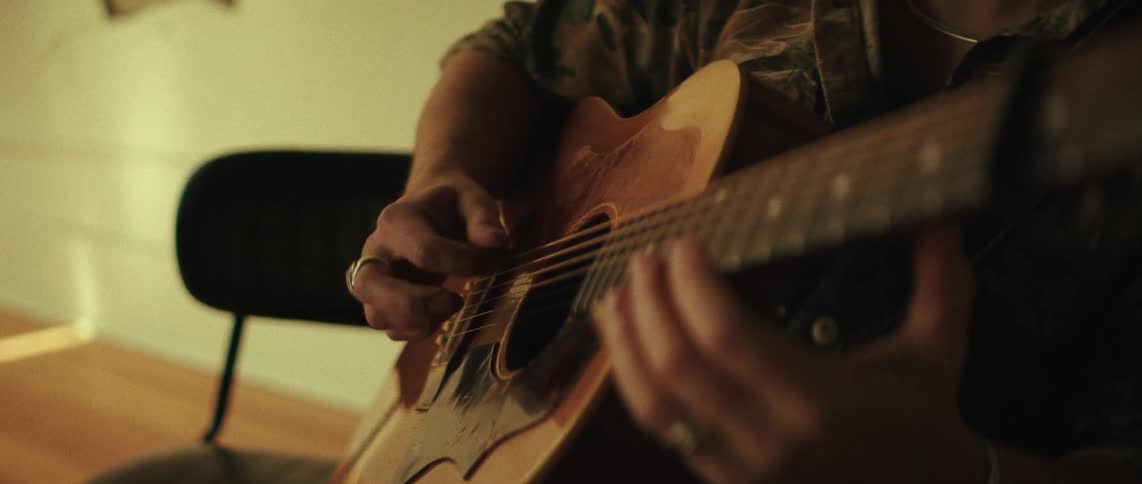 The video is a closeup shot focused on a persons hands playing an acoustic guitarthe player is seen plucking the strings with their right hand and fretting with their left suggesting a casual indoor musical performance or practice session