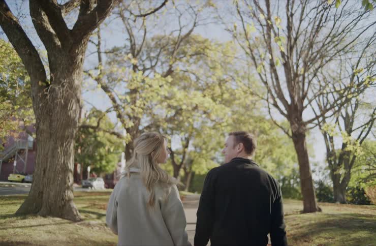 The couple walk on the sidewalk while holding hands