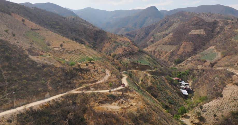 Aerial view of a winding road through dry mountains with buildings