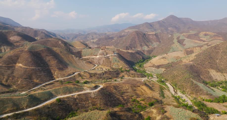 Aerial view of a winding road through terraced hills to a valley