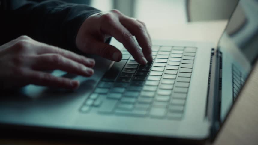 A persons hands typing on a laptop