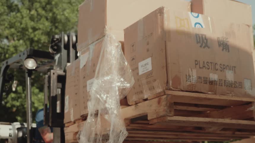 The man transports boxes on a pallet with a fork lift