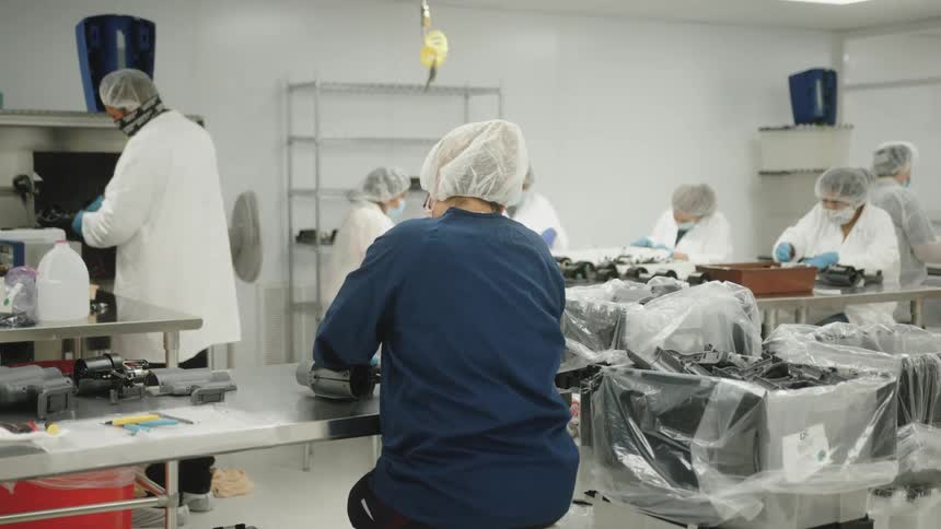 Workers wearing protective clothing assemble equipment in a cleanroom
