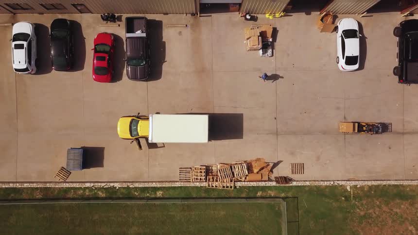 Aerial view of yellow box truck at dock with worker walking nearby