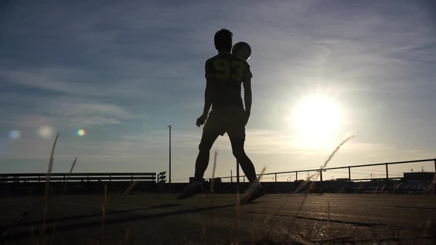 Man walks over and kicks a soccer ball on a cloudy day