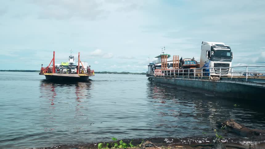 Ferry and cargo truck at a dock crossing a calm river