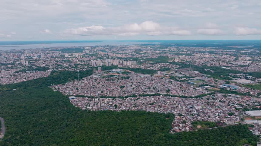 Aerial view of a large city surrounded by greenery under a cloudy sky