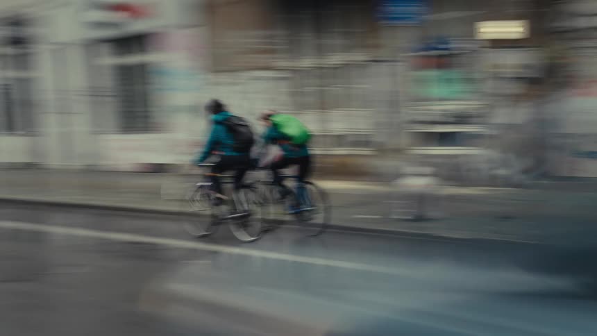 Two men ride their bikes in the city (slow shutter)