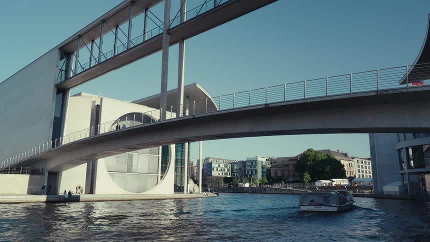 Large boat leaves a wake while heading under a bridge on the waterfront