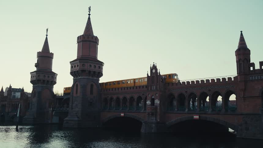 Yellow train crosses the upper level of a river bridge while other vehicles cross the lower level