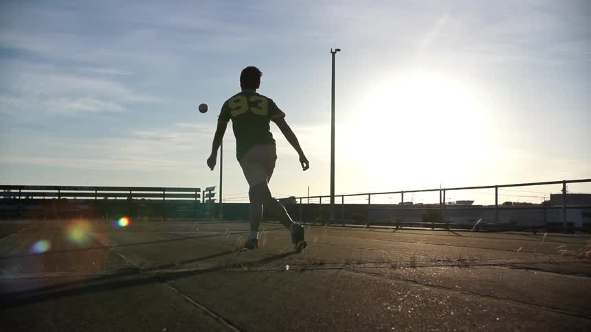 Man runs up and kicks a soccer ball into the sky