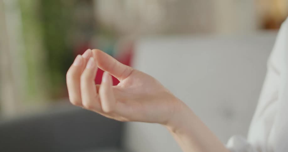 The woman sitting on the couch taps her fingers together