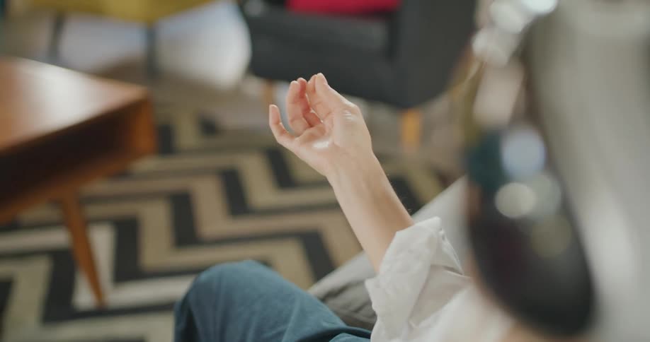 A woman sitting on a chair is making gestures with her hand and fingers