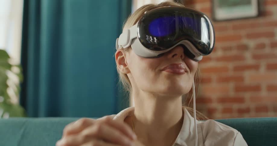 A blonde woman sitting on a couch wearing a virtual reality headset