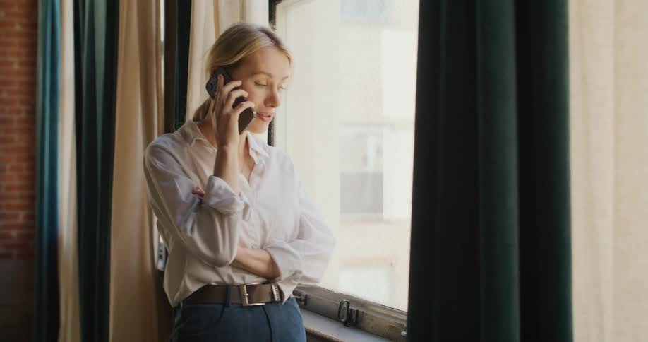 A woman talks on the phone near the window