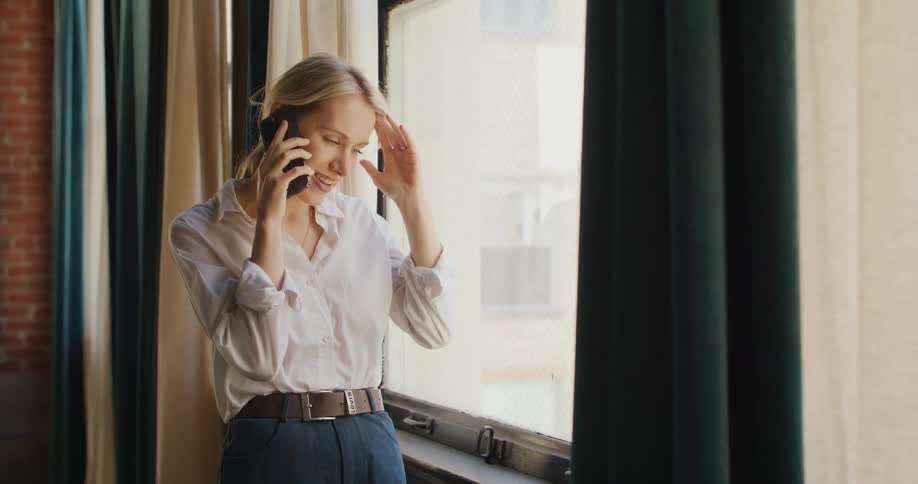 Woman making a phone call standing by office window
