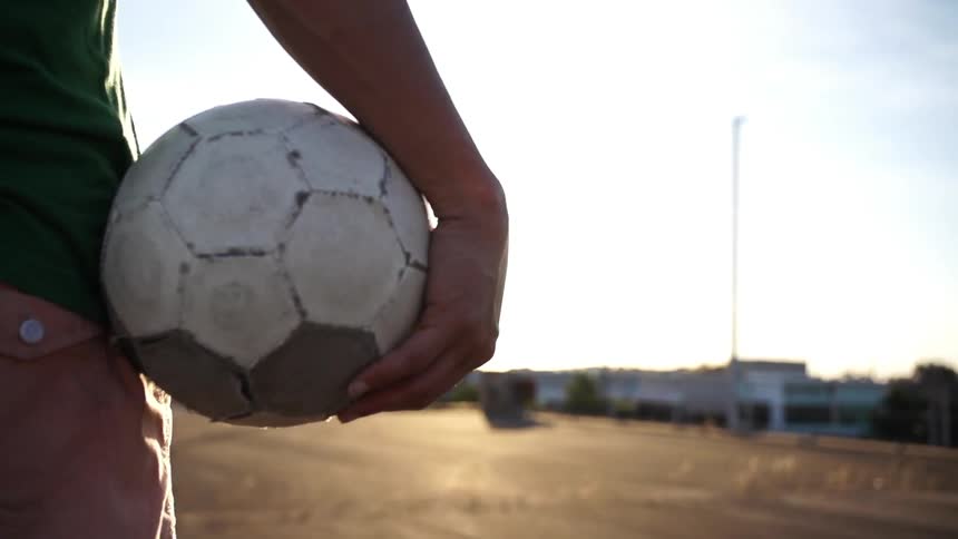 Person holding a soccer ball as the sun rises