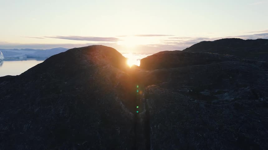 Aerial view of arctic sea and cliffs with icebergs under a beautiful sunset