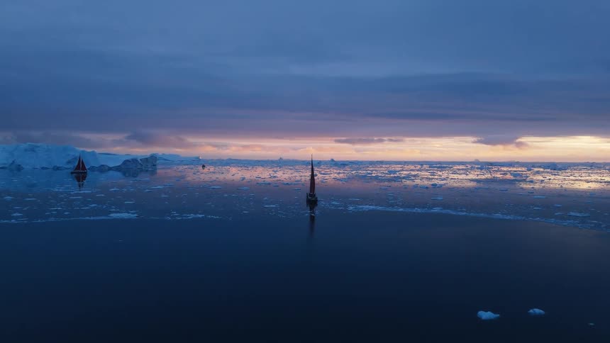 Boats sailing off the arctic coast among icebergs and floating ice
