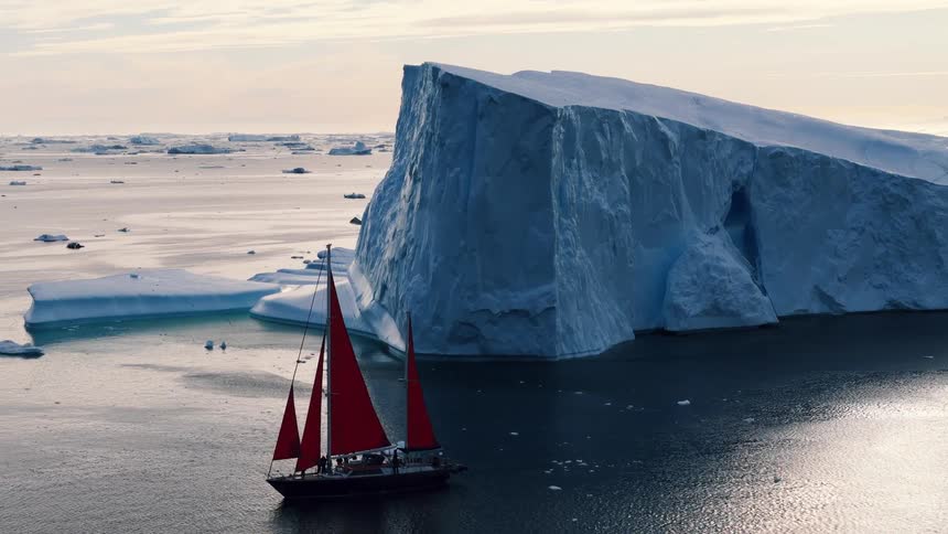 Melting ice floating on arctic water as a boat sails by an iceberg