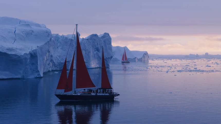 Two sailing ships navigate icy arctic waters surrounded by icebergs