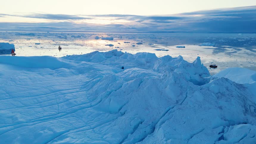 Melting glacier and ice on the water as boats sail along the arctic coast