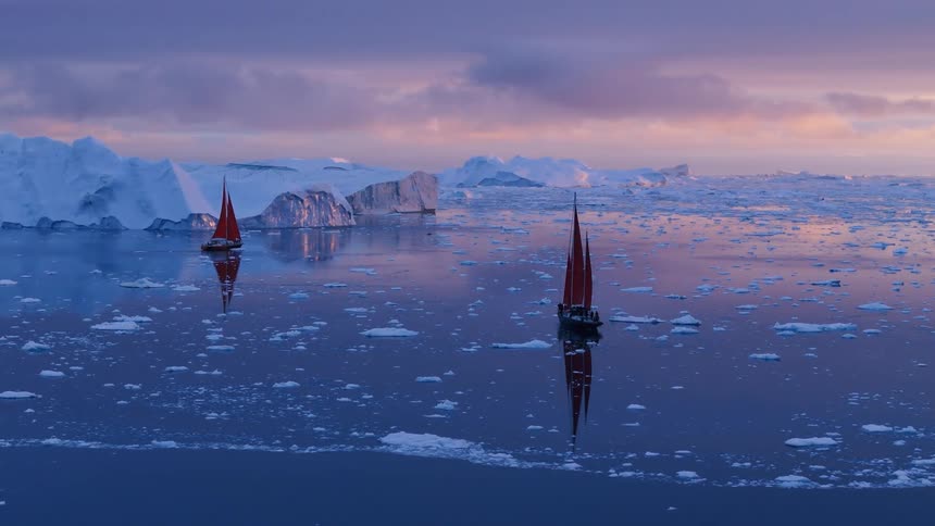 Boats sailing off the arctic coast among icebergs and floating ice