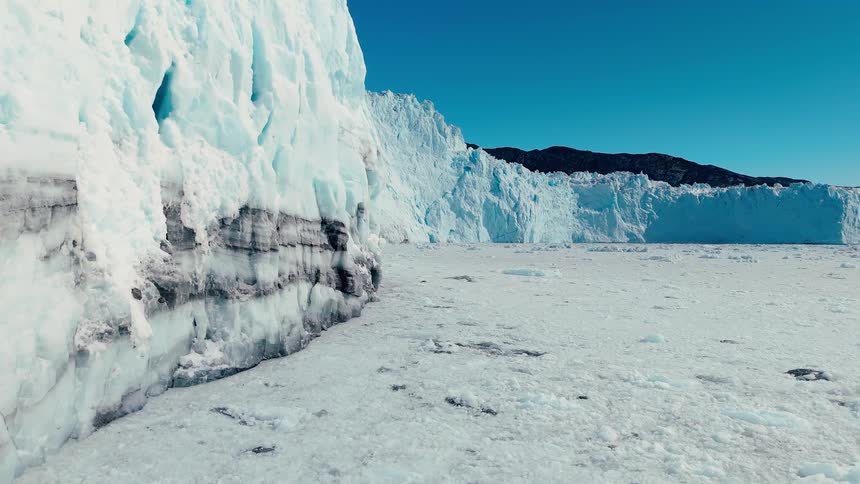 A glacier has been sheered off to show layers of sediment on the bottom